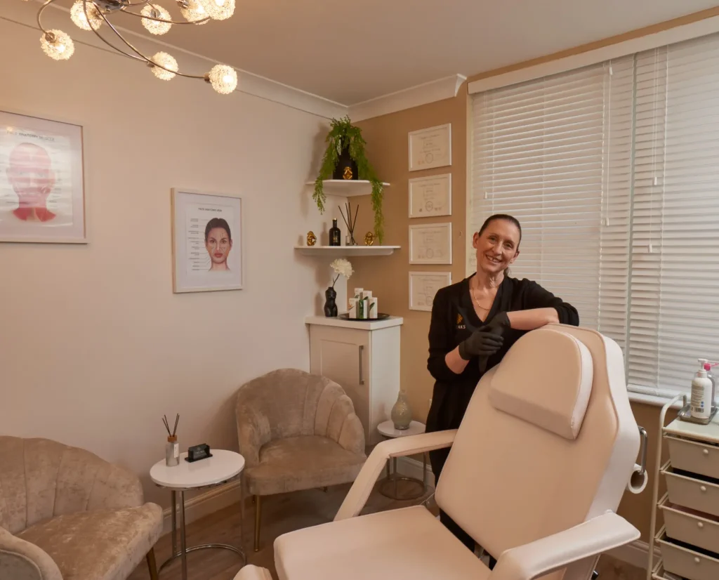 Modern aesthetics treatment room with professional standing beside treatment chair, featuring elegant decor and artistic wall displays