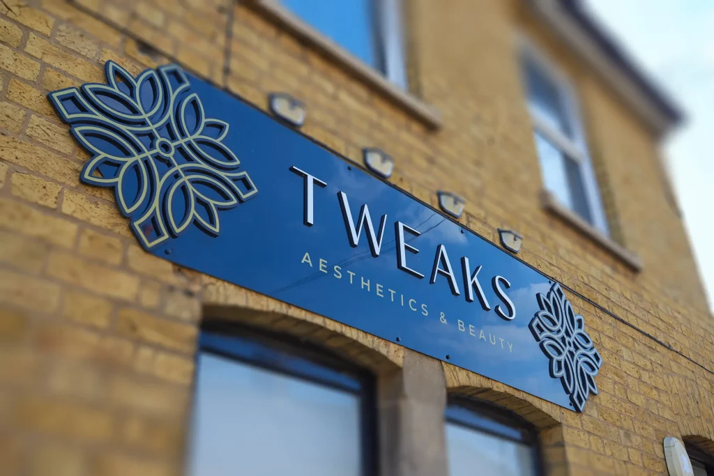 Tweaks Aesthetics & Beauty exterior signage on brick building with decorative floral logo
